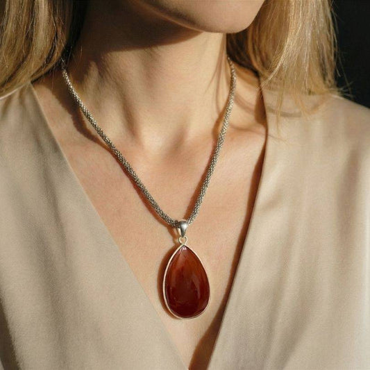 Carnelian Classic Pendant worn on model, highlighting its bold red-orange hue and silver bezel setting for creative energy and style.