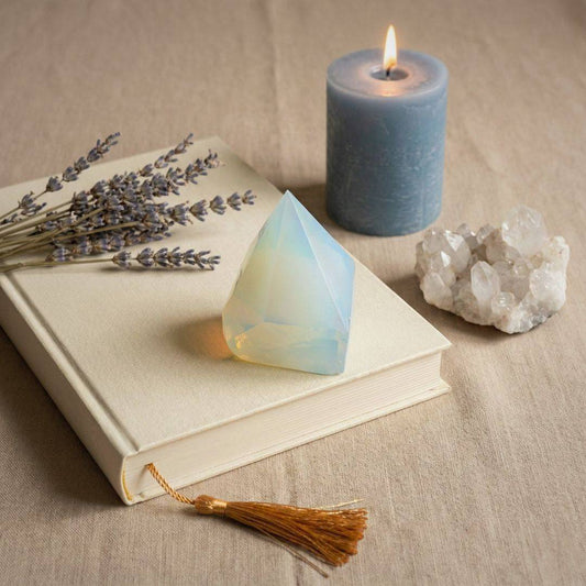 Opalite top polish point tower placed on a book with lavender, candle, and quartz, enhancing calm and balance in home decor settings.
