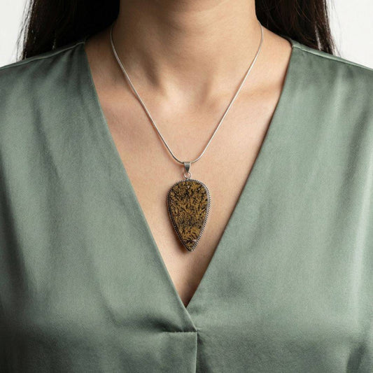 Psilomelane Jasper Pendant worn on a model, showcasing its bold teardrop design and earthy tones for grounding and integration.