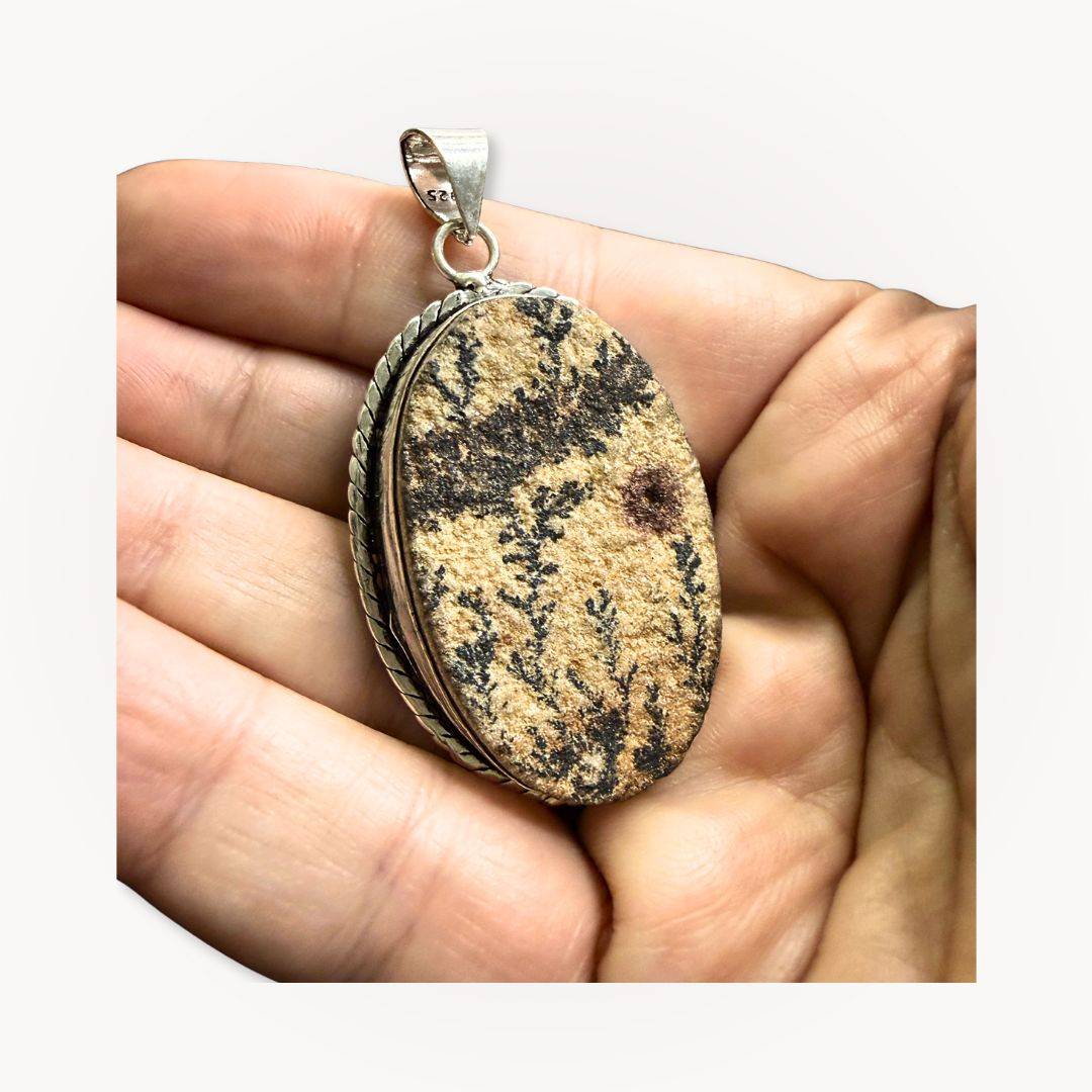 Handheld Psilomelane Jasper Pendant highlighting earthy tones and detailed silver setting. A grounding jewelry piece for mindful wearers.