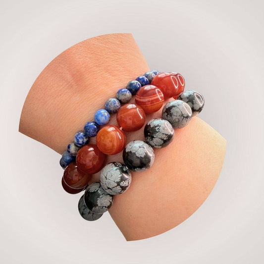 Stacked gemstone bracelets including Red Botswana Agate 12mm Beaded Bracelet, styled on wrist for grounding and stability in everyday wear.
