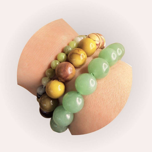 Stacked crystal bracelets including the 6mm Serpentine Bracelet for kundalini awakening, shown on wrist with earthy-toned gemstone jewelry.