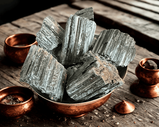 Raw black tourmaline rough from Brazil in a copper bowl on rustic wood — large striated chunks with natural sheen, 50g–120g pieces.