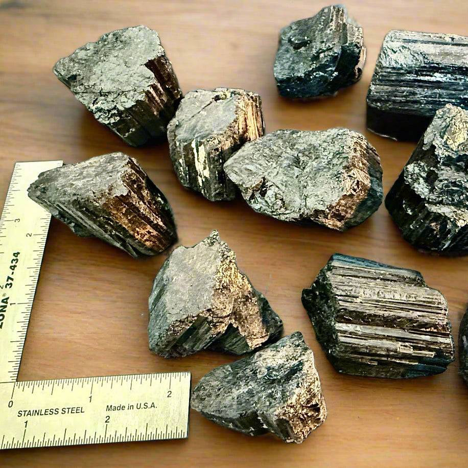 Group of Brazilian black tourmaline rough with metal rulers for scale, highlighting size range and natural ridges.