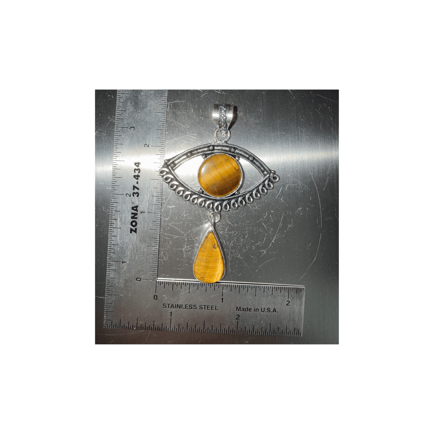 Tigers Eye Evil Eye Drop Pendant in Sterling Silver featuring a round eye design with a teardrop charm, shown next to a ruler for scale.
