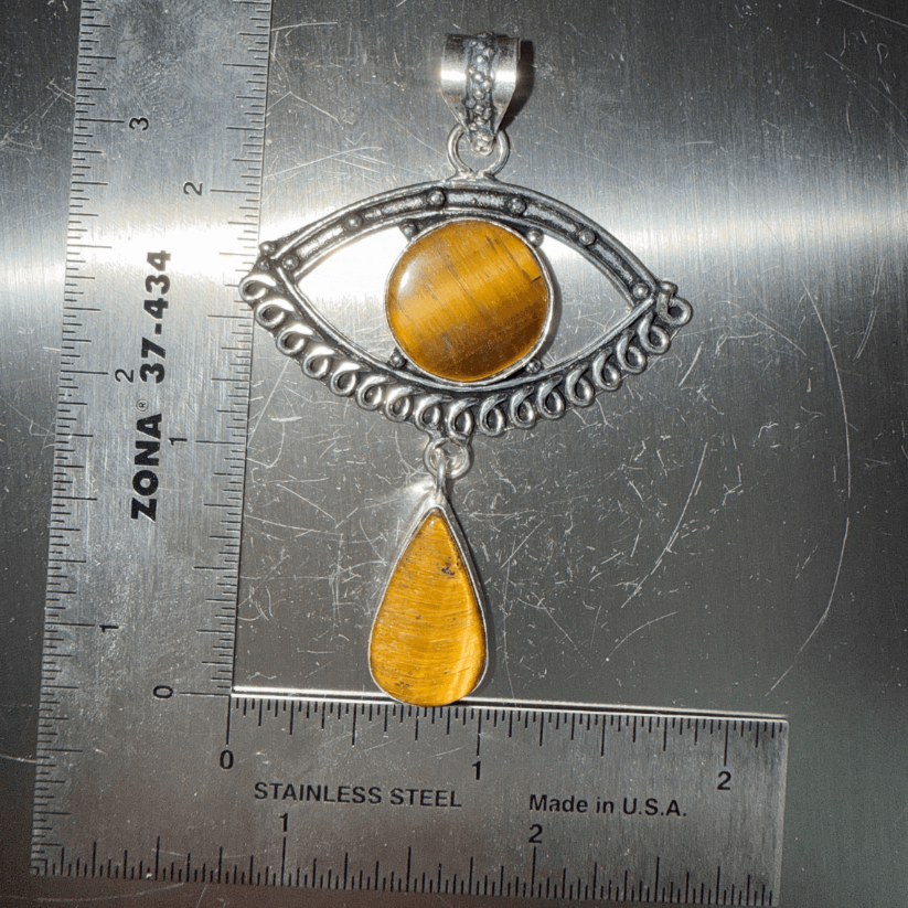 Tigers Eye Evil Eye Drop Pendant in Sterling Silver featuring a round eye design with a teardrop charm, shown next to a ruler for scale.