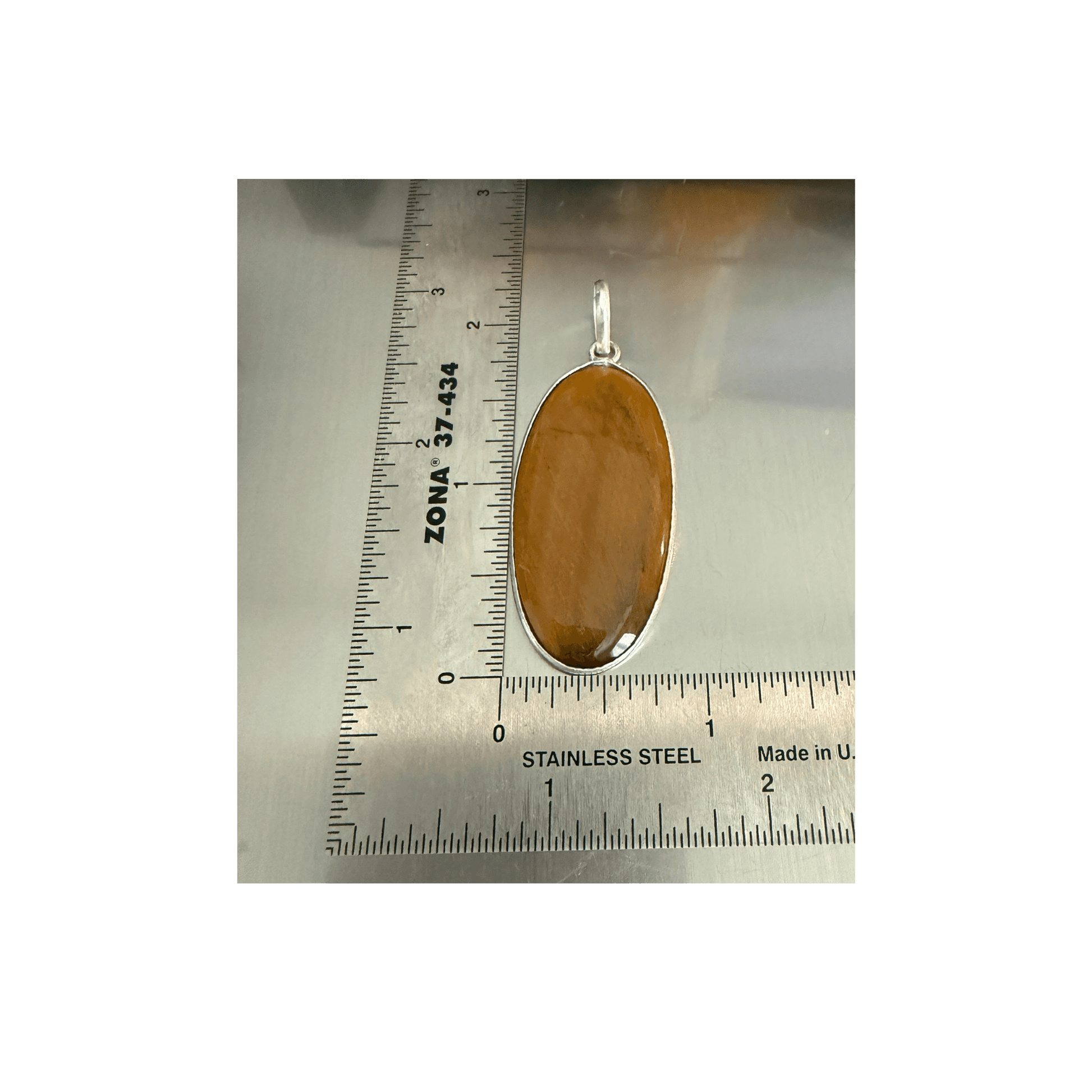 Tigers Eye Oval Pendant in sterling silver with warm golden-brown hues, shown next to a ruler for scale. Enhances courage, clarity, and protection.