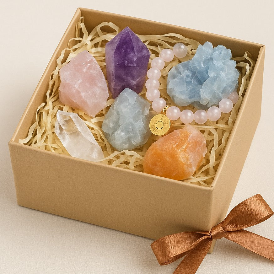 Crystal gift box with assorted raw stones and a rose quartz bracelet.