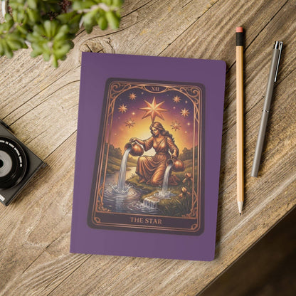 The Star Tarot Softcover Journal placed on a rustic desk with pencil and camera, showcasing its artistic design for creative and spiritual use.