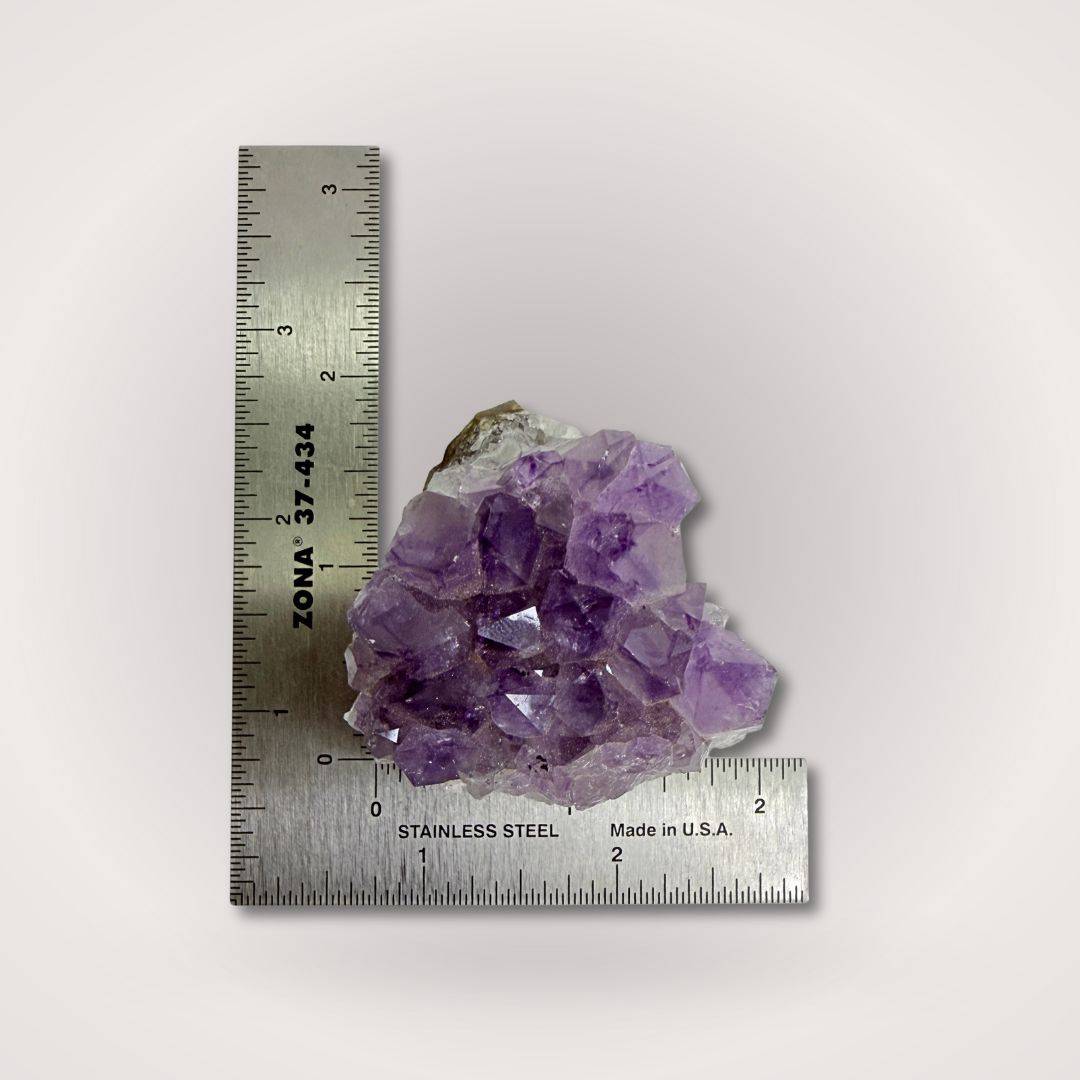 Compact Amethyst Geode Cluster Piece 50–100g shown with ruler for scale, featuring vibrant purple hues and natural crystal formation.