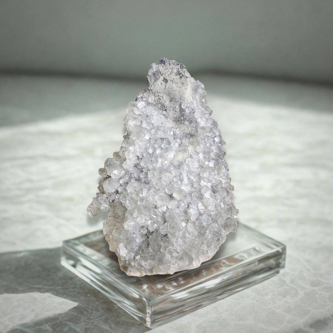 Apophyllite Cluster - Collector Specimen 497g displayed on a clear stand, highlighting its sparkling facets and natural light reflection.