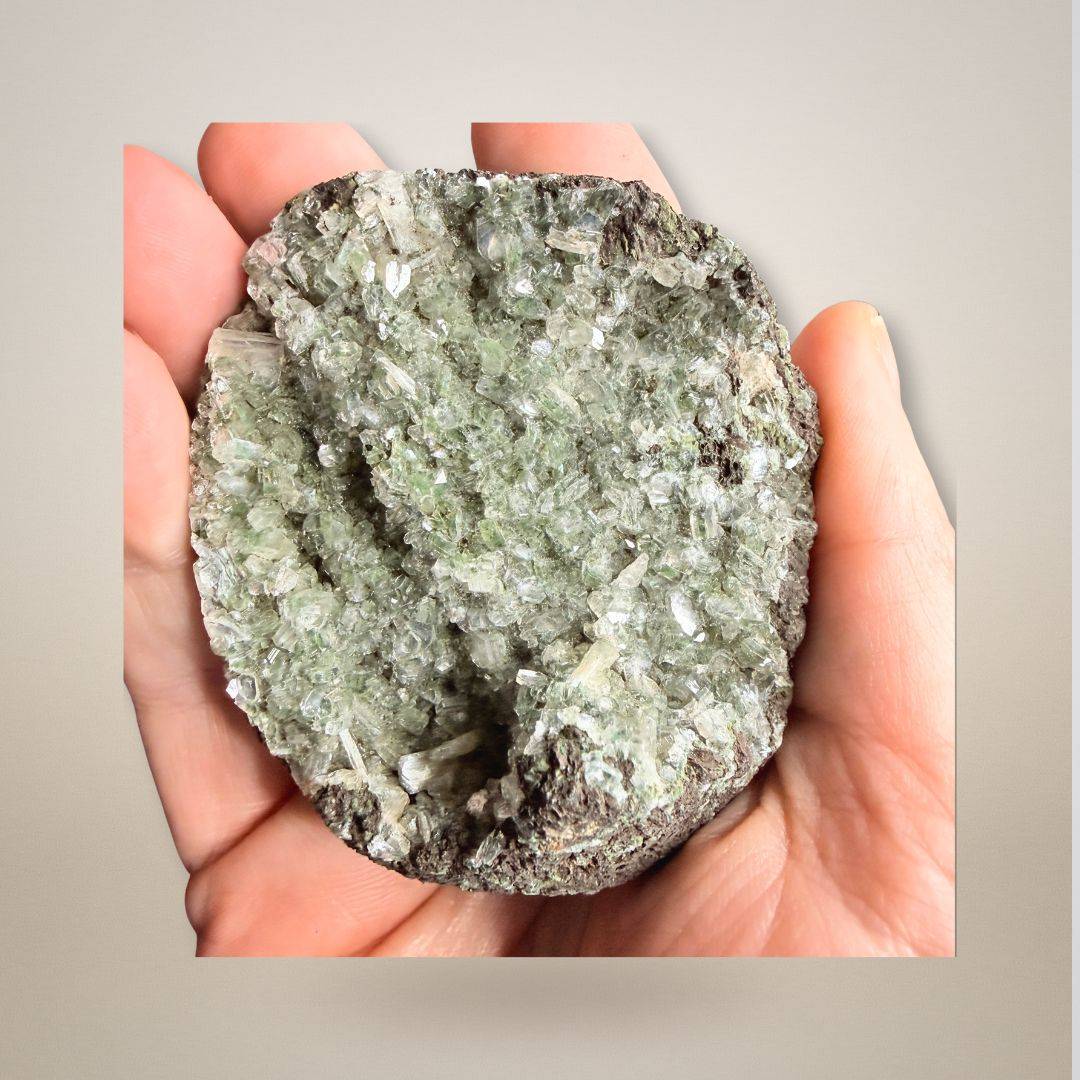 Hand holding Green Apophyllite Stilbite Cluster Geode Specimen, showcasing its compact 114g size and intricate crystal formations.
