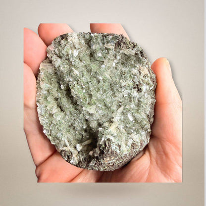 Hand holding Green Apophyllite Stilbite Cluster Geode Specimen, showcasing its compact 114g size and intricate crystal formations.