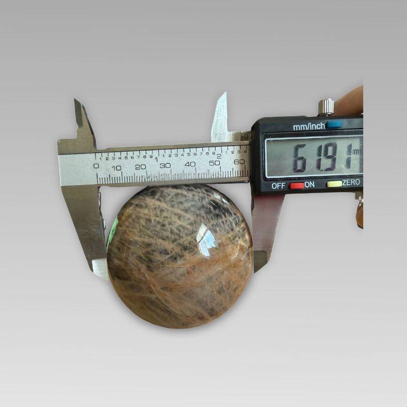 Soulful Black Moonstone Sphere measuring 61.91mm with digital caliper, ideal for intuition and meditation rituals in crystal collections.