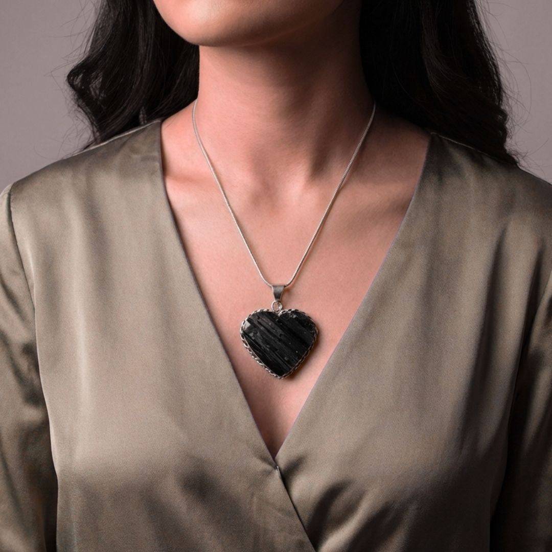 Woman wearing Black Tourmaline Heart Pendant necklace, showcasing its elegant design and grounding energy in a stylish jewelry setting.