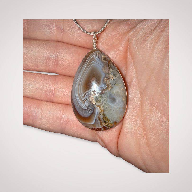 Botswana Agate Pendant with Parallax Ghost Effect in hand for scale