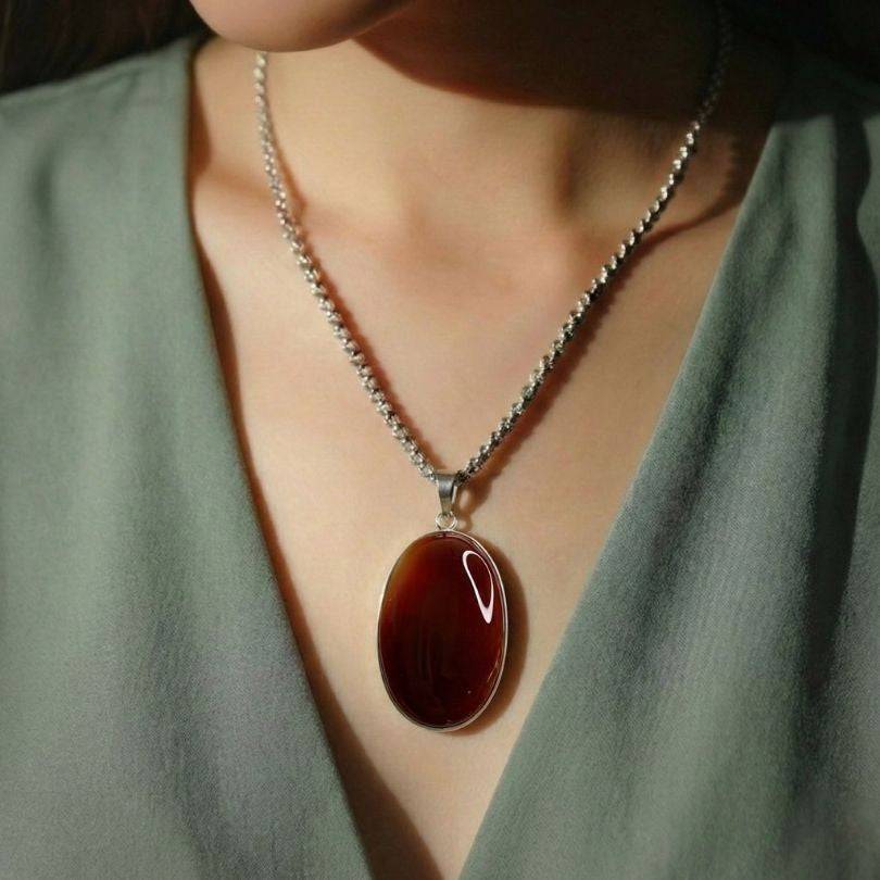 Carnelian Statement Pendant worn on model, showcasing its bold red-orange hue and silver bezel setting for a confident, energizing look.
