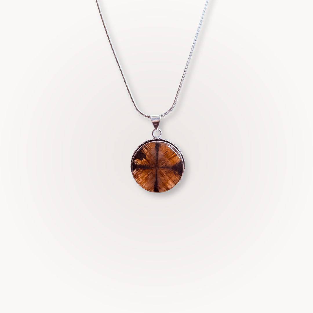 Single round Chiastolite Cross Stone Pendant on a silver necklace, highlighting its earthy tones and sacred cross formation for grounding energy.