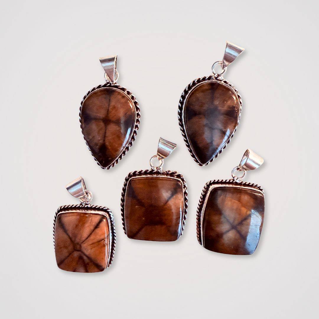 Chiastolite Cross Stone Pendants in teardrop and square shapes with silver trim, showcasing natural cross patterns for spiritual grounding.