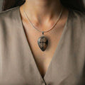 Teardrop Chiastolite Cross Stone Pendant worn on a silver chain, highlighting its protective cross design and elegant earthy tones.