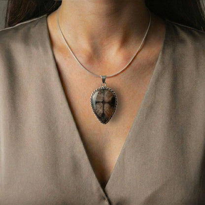 Teardrop Chiastolite Cross Stone Pendant worn on a silver chain, highlighting its protective cross design and elegant earthy tones.