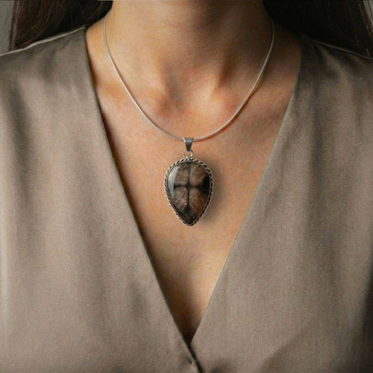Teardrop Chiastolite Cross Stone Pendant worn on a silver chain, highlighting its protective cross design and elegant earthy tones.