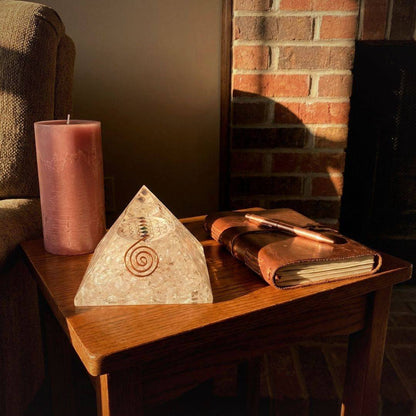 Clear Quartz Flower of Life Orgonite Pyramid placed on a wooden table, ideal for meditation spaces and spiritual home decor.