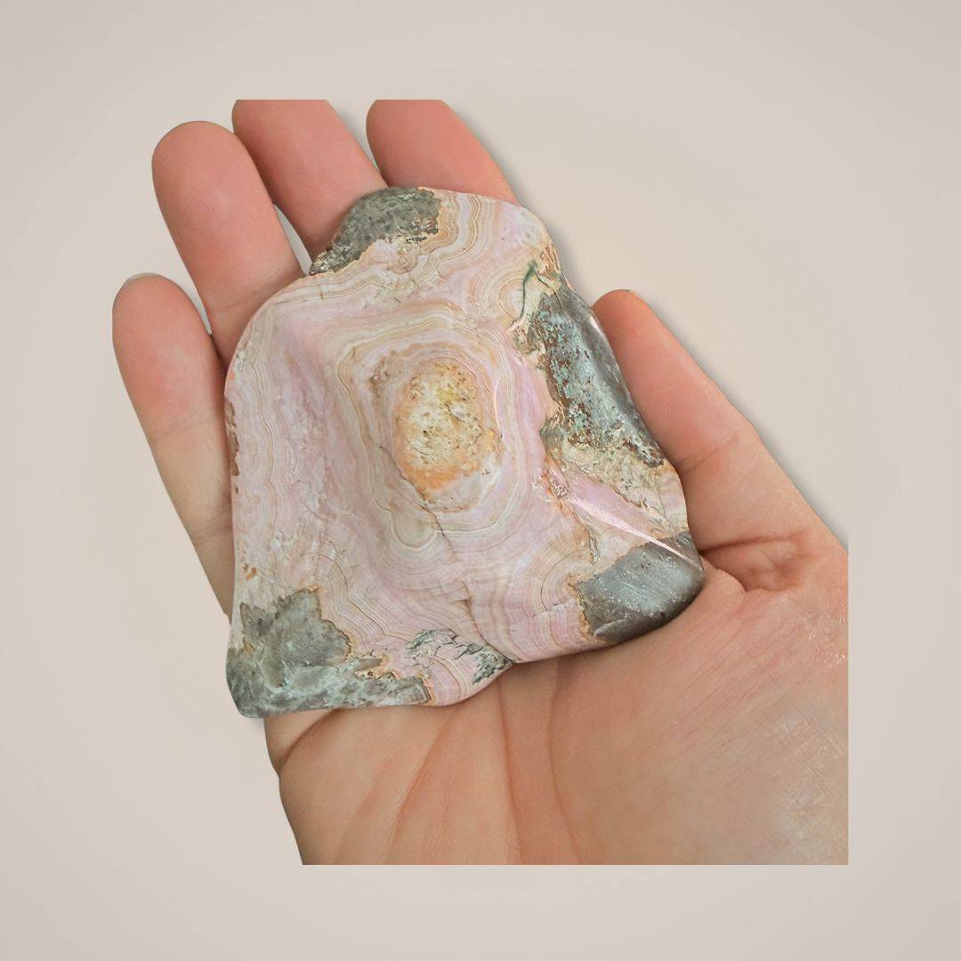 Hand holding pink and green Cobaltoan Calcite mineral specimen with layered banding