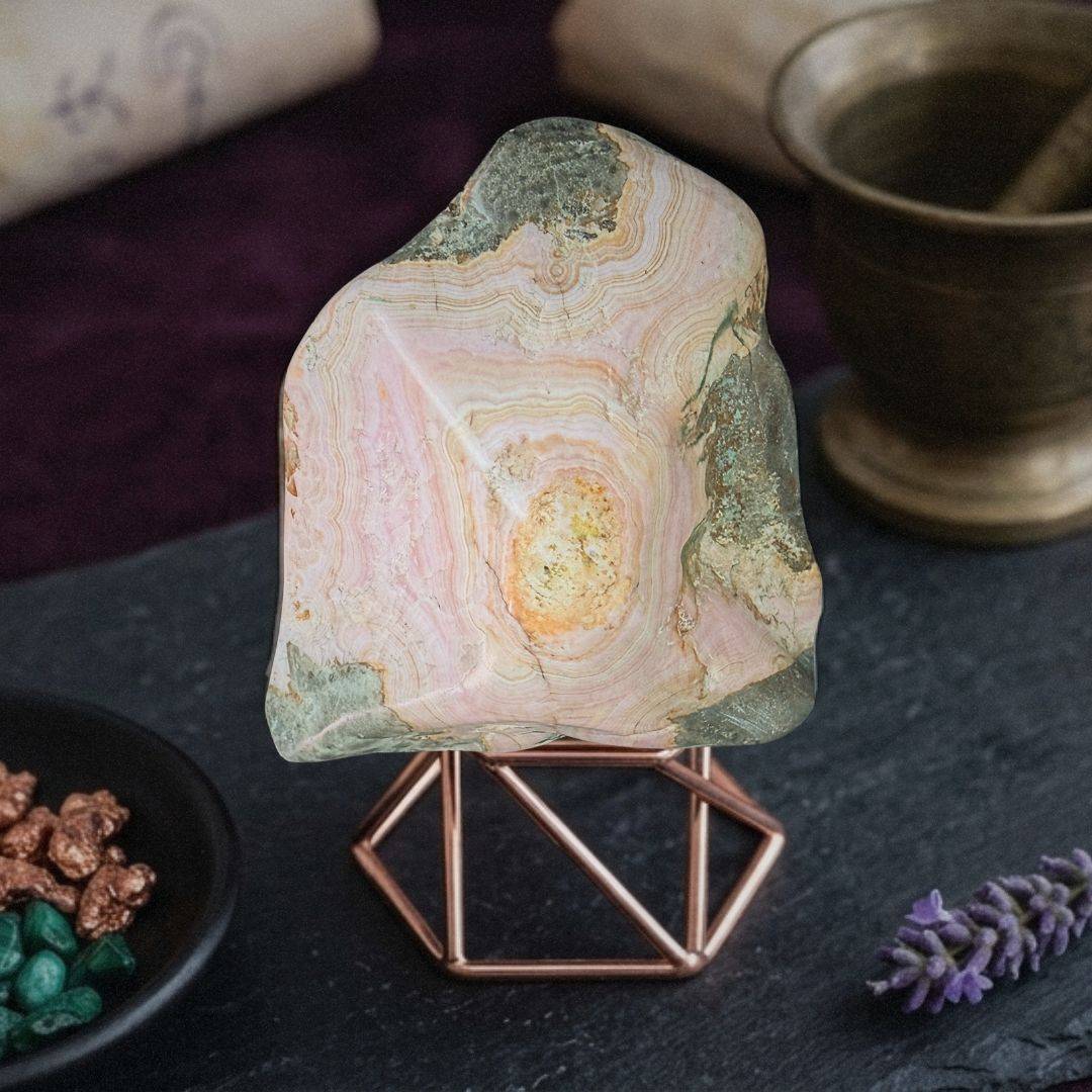 Pink and green Cobaltoan Calcite stalactite on display stand with natural cave patterns