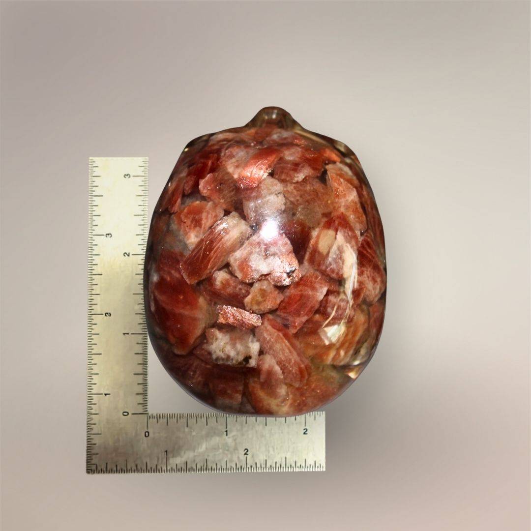 Rear view of the Confetti Sunstone skull orgonite beside rulers showing its approximately 4.13-inch height and 2.72-inch width.