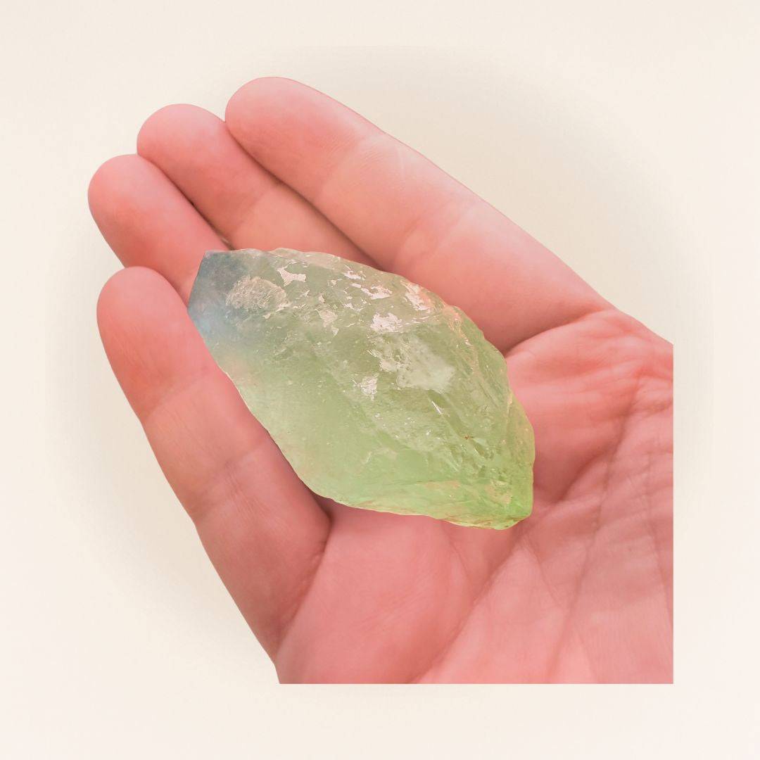Hand holding a green fluorite raw piece, highlighting its size and clarity. Supports focus and calm in crystal healing practices.