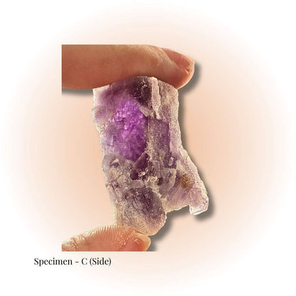 Brazilian Purple Fluorite crystal specimen C held between fingers, showcasing natural clarity and deep violet hues for focus and alignment.