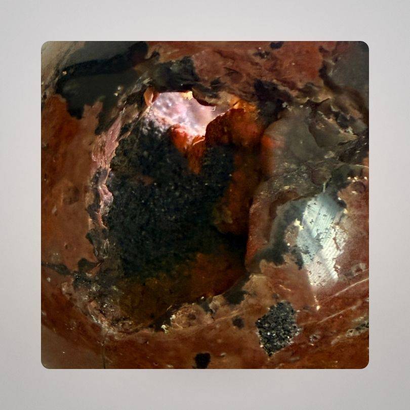 Close-up of Red Fox Agate Sphere (346g) showing intricate hematite-lined cavity, highlighting its rare mineral formation from Argentina.