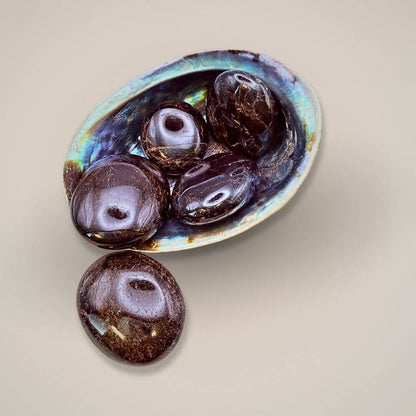 Garnet gemstone in shell dish with beads and hand for size comparison
