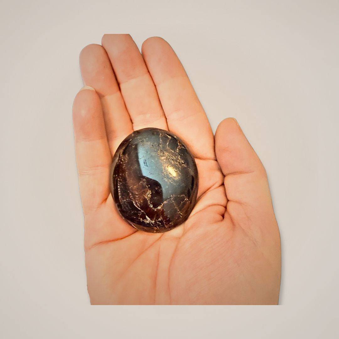 Close-up of garnet palm stone held in hand for size reference