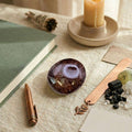 Garnet palm stone on textured surface with candle and book