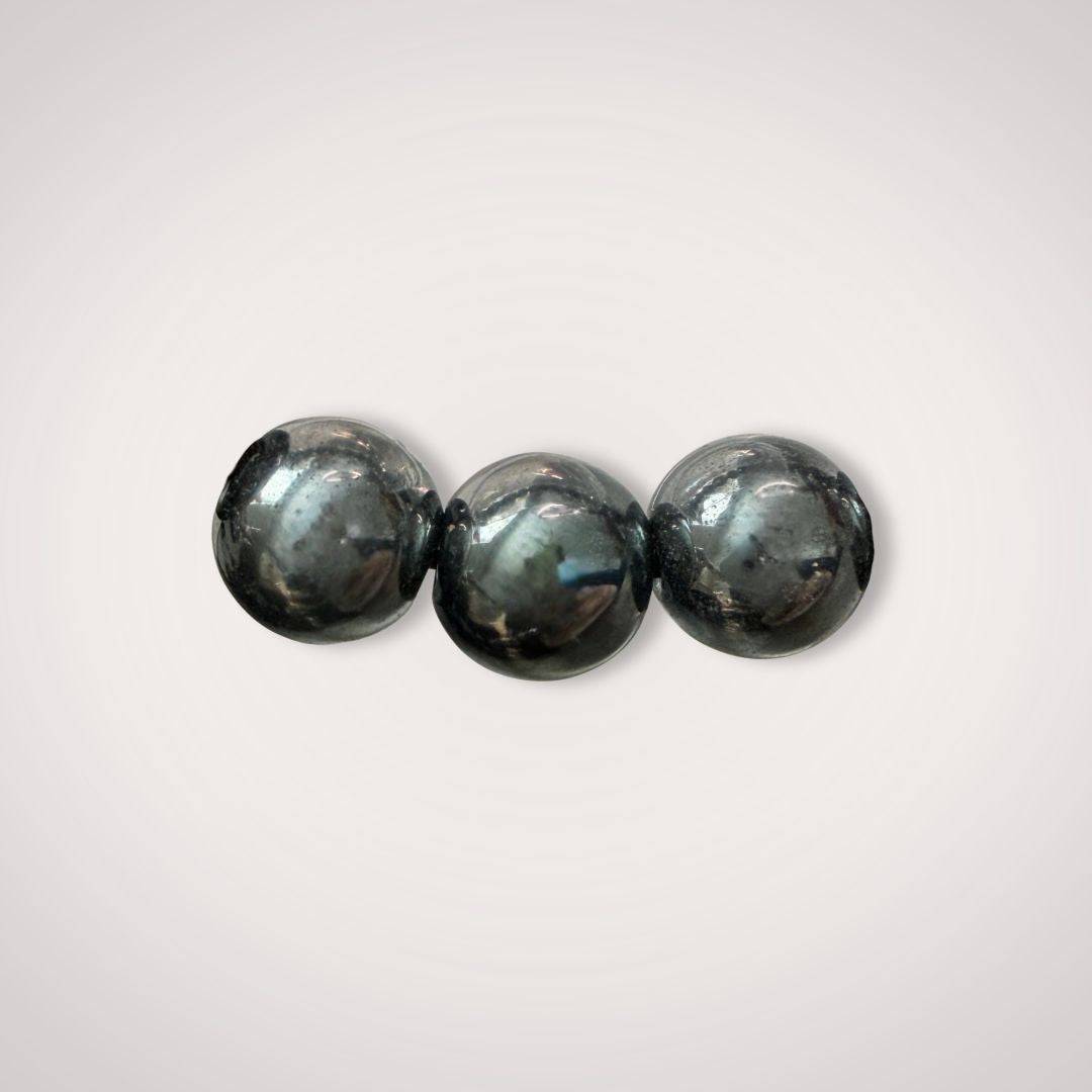 Close-up of three polished 12mm Hematite beads from the Hematite 12mm Beaded Bracelet - Grounding & Stable Protective, showcasing natural shine.