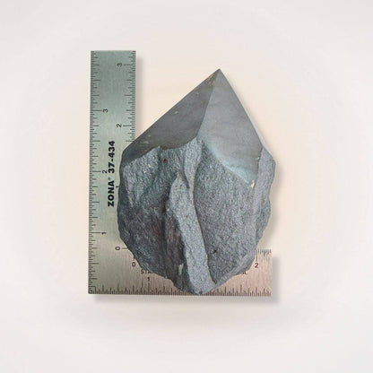 Hematite top polish point tower shown with rulers for scale, highlighting its size and natural raw base for grounding energy practices.