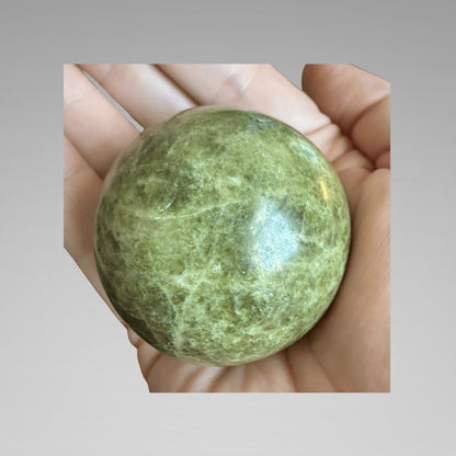 Green Infinite Stone Sphere - Heart Chakra Aid made from Serpentine & Chrysotile, shown in hand for size reference. Ideal for energy healing and balance.
