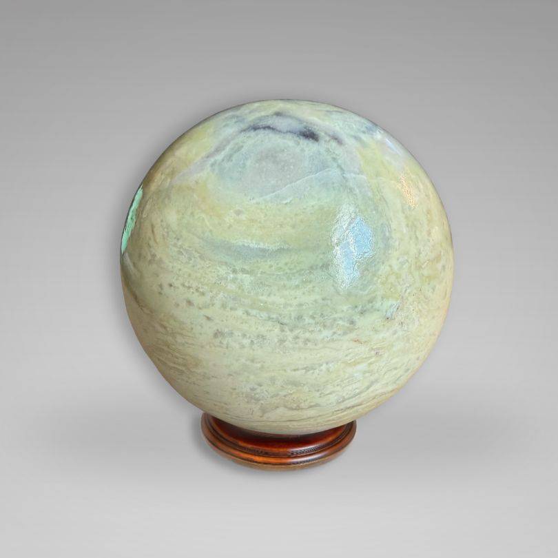 Polished Infinite Stone Sphere from Peru on wooden stand, ideal for Heart Chakra healing and energy work, weighing 220–326 g.