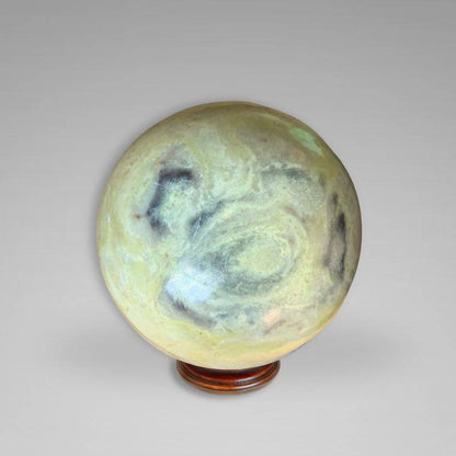 Green and cream-toned Infinite Stone Sphere from Peru on display stand, used for Heart Chakra healing and gemstone collection.