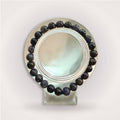 Iolite Beaded Bracelet 8mm displayed on a clear round stand, showcasing deep blue-violet beads for intuition and mental clarity.