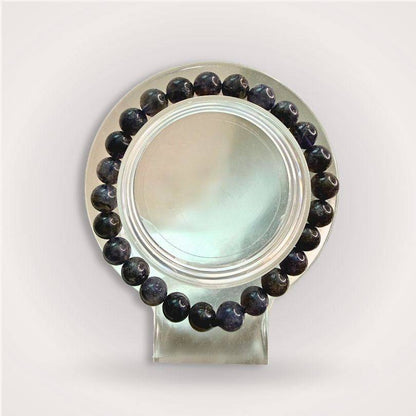 Iolite Beaded Bracelet 8mm displayed on a clear round stand, showcasing deep blue-violet beads for intuition and mental clarity.