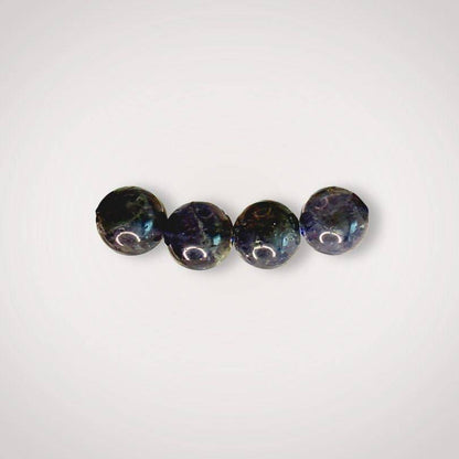 Close-up of four 8mm Iolite beads showing natural variations in color and clarity, ideal for enhancing inner vision and focus.