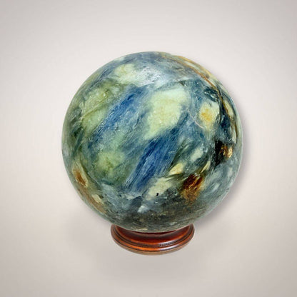 Blue Kyanite & Quartz Sphere 61mm with radiant blue, green, and golden mineral patterns on a wooden stand. Ideal for alignment and insight rituals.