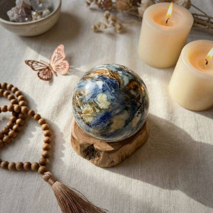 Blue Kyanite & Quartz Sphere 61mm displayed on a wooden base with candles and crystals, enhancing spiritual ambiance and intuitive clarity.