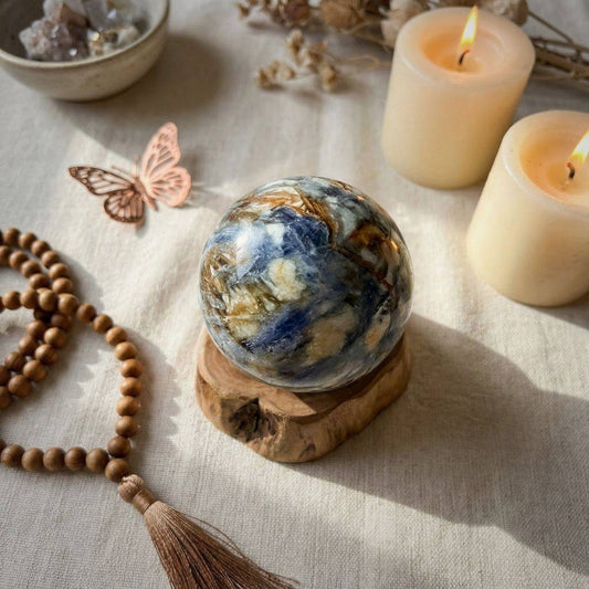 Blue Kyanite & Quartz Sphere 61mm displayed on a wooden base with candles and crystals, enhancing spiritual ambiance and intuitive clarity.