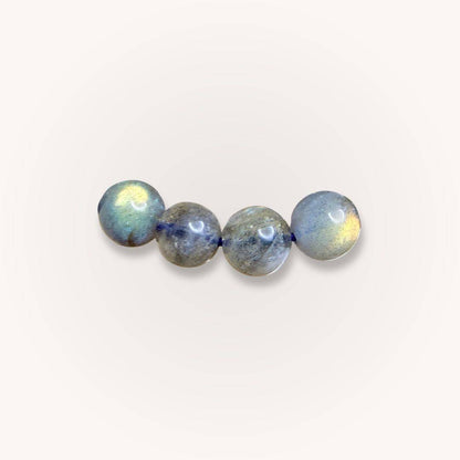 Close-up of 7mm Madagascar Labradorite beads showing iridescent flashes, part of the Intuition & Protection Jewelry collection.
