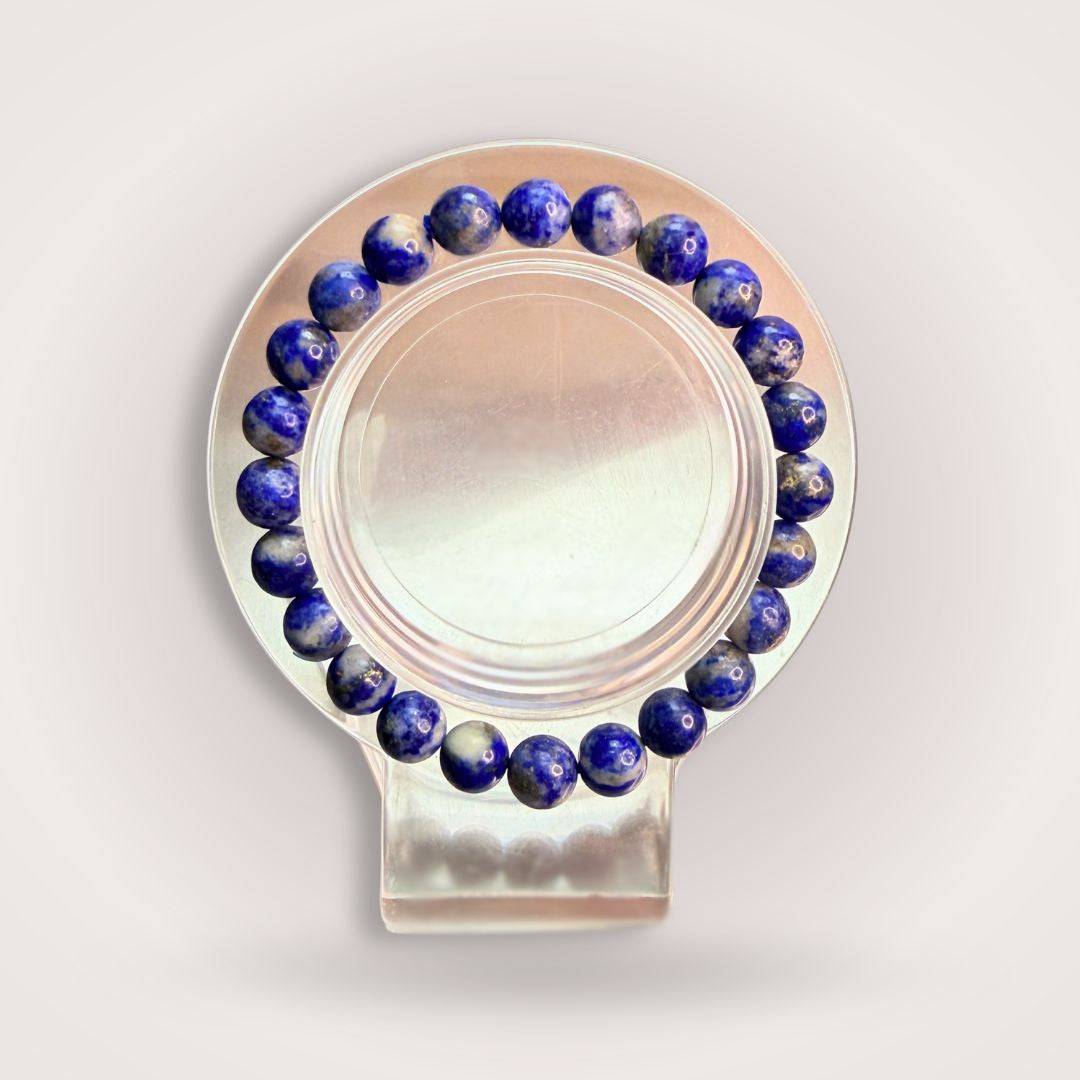Lapis Lazuli 8mm Beaded Bracelet - Wisdom | Intuition & Truth displayed on a clear round stand, showcasing deep blue polished stones.