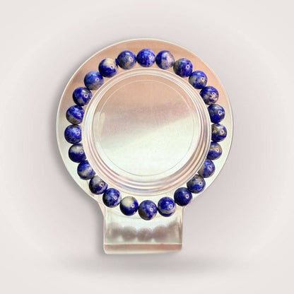Lapis Lazuli 8mm Beaded Bracelet - Wisdom | Intuition & Truth displayed on a clear round stand, showcasing deep blue polished stones.